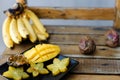 Close up mango and carambola on plate near bananas on wooden table.