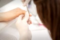 Close up of manicure master with manicure scissors removes cuticles on female nails at a beauty salon. Royalty Free Stock Photo