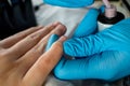 Close up of manicurist wearing blue gloves painting pink nails