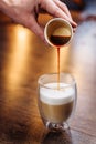 Close-up of a mans hand pouring freshly brewed espresso in a coffee machine from a small paper cup into a transparent cup with Royalty Free Stock Photo