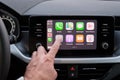 Close up mans hand touching an icon in the Apple Carplay on car dashboard screen, September 2020, San Francisco, USA.