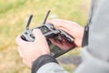 Close up mans hands holding drone remote controller with smartphone in the field. Concept of aerial shooting and flying