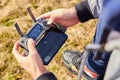 Close up mans hands holding drone remote controller with smartphone in the field. Concept of aerial shooting and flying, San