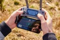 Close up mans hands holding drone remote controller with smartphone in the field. Concept of aerial shooting and flying, San