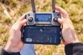 Close up mans hands holding a drones remote controller. A aerial shoot of a bridge is on the screen of smartphone. Real footage