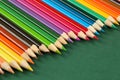 Close up of many, bright multi colored wooden pencils in a row on a dark green background with copy space. Selective focus and sha Royalty Free Stock Photo