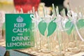 Close-up of many empty bottles for lemonade or a cocktail with a striped straw and a green leaf decor and a sign saying Keep calm