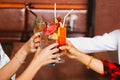 Close up of many friends hands holding a glass of alcoholic cocktail for social gathering and celebration in bar.