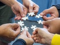 Close-up of many people hands holding a jigsaw puzzle piece in circle together Royalty Free Stock Photo