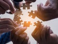 Close-up of many people hands holding a jigsaw puzzle piece in circle together with sunlight effect Royalty Free Stock Photo