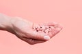 Close-up of many pink pills in woman hand on pink background. Medical concept of medicine treatment, vitamins Royalty Free Stock Photo