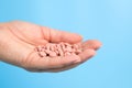 Close-up of many pink pills in woman hand on blue background. Medical concept of medicine treatment, vitamins Royalty Free Stock Photo