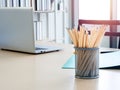 Close-up many wood pencils in container with laptop computer on wooden desk in the office