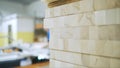 Close-up of many wooden wooden bars in a workshop and blurred silhouette of man working with the circular saw at the Royalty Free Stock Photo