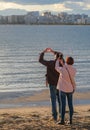 Close up of married couple takes pictures of a beautiful sunset over the sea