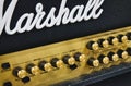 Close-up of a Marshall stack amplifier head showing the white logo on the grill mesh and buttons
