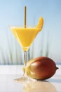 A martini glass with mango juice, a straw and an apricot slice next to a fresh looking mango Royalty Free Stock Photo