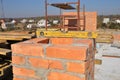 A close-up on a masonry chimney construction using a spirit level. An unfinished roof with construction materials, scaffolding, Royalty Free Stock Photo