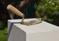 A close up on a masonry trowel, a working tool of a bricklayer on an autoclaved aerated concrete block