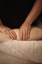 Close-up of the masseur hands on the client leg. Vertical image. No face.