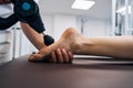 Close-up of masseur rubbing woman foot with massage percussion device in rehab clinics therapy room