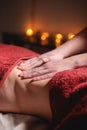 Close-up of masseur`s male hands doing abdominal massage to a female client in a dark office against the background of Royalty Free Stock Photo