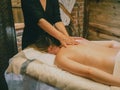 close-up masseuse hands doing back massage to young caucasian woman in spa center wood cabin Royalty Free Stock Photo