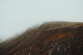 Close up of a massive red mountain in the north of europe during a foggy day with mist all over it with copy space Royalty Free Stock Photo
