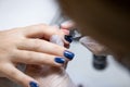 Close-up, the master evens the color of the manicure with blue, applying gel polish on it with a brush