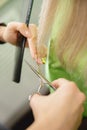 Close-up of master hairdresser shears with scissors dry ends of woman hair in salon