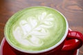 match tea latte with a latte art in red ceramic mug in a coffee shop Royalty Free Stock Photo