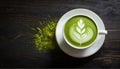 Close up of matcha green tea latte in white cup on dark empty wood table