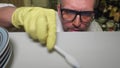 Close up of mature man in glasses and gloves on hands cleaning white shelf of cuboard using tooth brush. Preventing