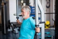 Close up of mature man at the gym doing exercise alone lifting weight to build his body and be fit - active pensioner senior