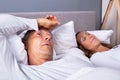 Man With Insomnia Lying On Bed Next To His Wife