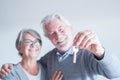 Close up of mature man holding a key of a new home or house or some property of both - couple of seniors and pensioners smiling Royalty Free Stock Photo