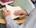 Close-up of mature student's hands turning book