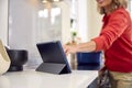 Close Up Of Mature Woman In Kitchen At Home Cooking Meal Following Recipe On Digital Tablet