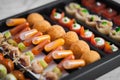 Close-up of meatballs in a box with mixed gourmet hors d'oeuvres, each skewered with transparent sauce container.