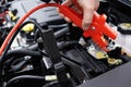 Close-Up Of Mechanic Attaching Jumper Cables To Car Battery