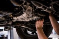 Close up of a mechanic hands repaires lifted car