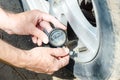 Hand of mechanic checking air pressure in tire with gauge closeup Royalty Free Stock Photo