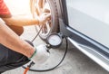 Close up mechanic inflating tire and checking air pressure with gauge pressure