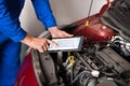 Mechanic Using Digital Tablet While Examining Car Engine