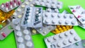 Close up of medical blister packs with tablets on green background. Packs with various tablets. Concept of threat of