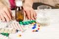 Close-up of medical bright colored blisters with pills and capsules with medicines and a glass of water. Women`s hands touch the