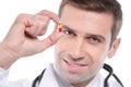 Close up of medical doctor holding small yellow-red pill Royalty Free Stock Photo