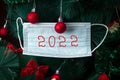 Close-up of medical mask on the Christmas tree with the inscription 2022. Covid pandemic concept in new year