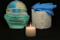 Close-up - a candle of remembrance against the background of a globe, rubber gloves and toilet paper