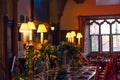 Close up medieval british castle interior dining table with plates, flowers and lamps. Warm light. Selective focus. copy space